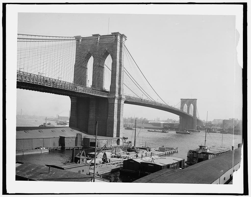 Archival photograph of Brooklyn Bridge above waterfront piers, cataloged circa 1900 by the Library of Congress